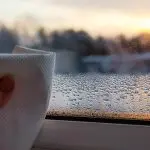 Person wiping condensation from a window, illustrating the effects of humidity control on indoor air quality and comfort.