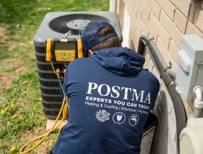 HVAC technician from Postma Heating, Cooling, Plumbing & Electrical performing air conditioning diagnostics on a residential outdoor AC unit. Technician is wearing branded Postma hoodie with slogan "Experts You Can Trust" and service icons, emphasizing professional AC repair and maintenance.