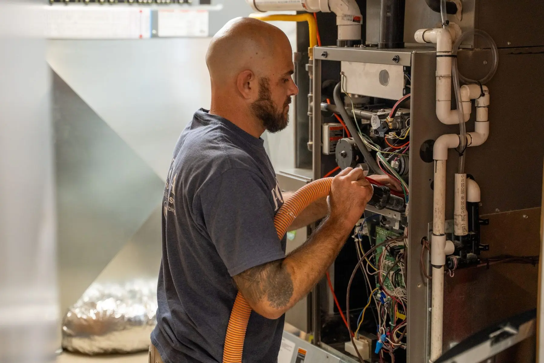 HVAC technician performing furnace maintenance, inspecting and cleaning components of a residential furnace in Chatham, Ontario.
