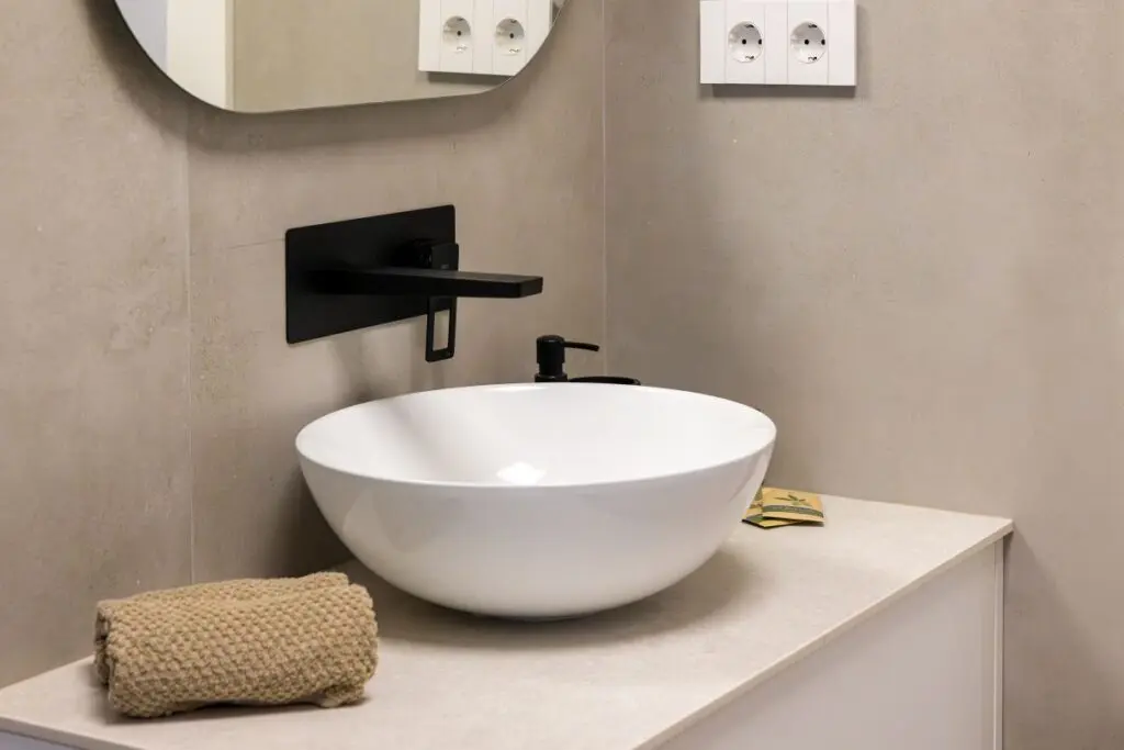 Modern bathroom sink with minimalist design featuring round basin and matte black wall mounted faucet