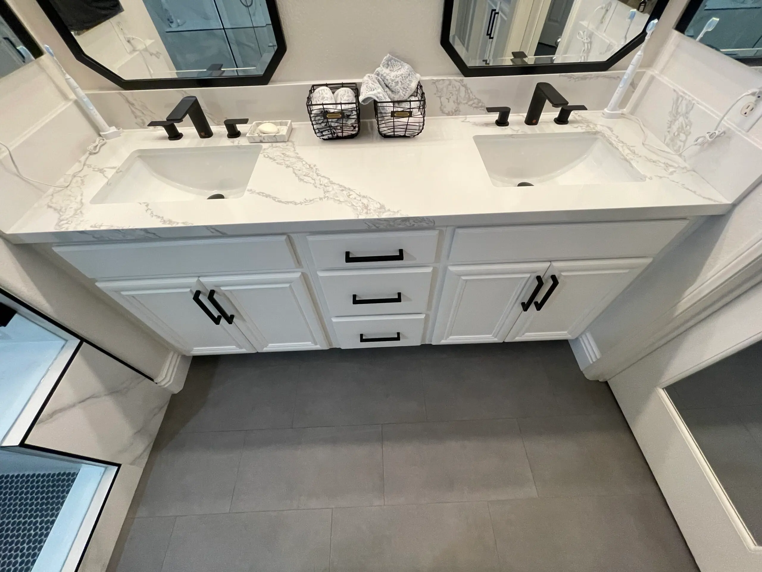 White floating vanity with black accents and two mirrors above sinks