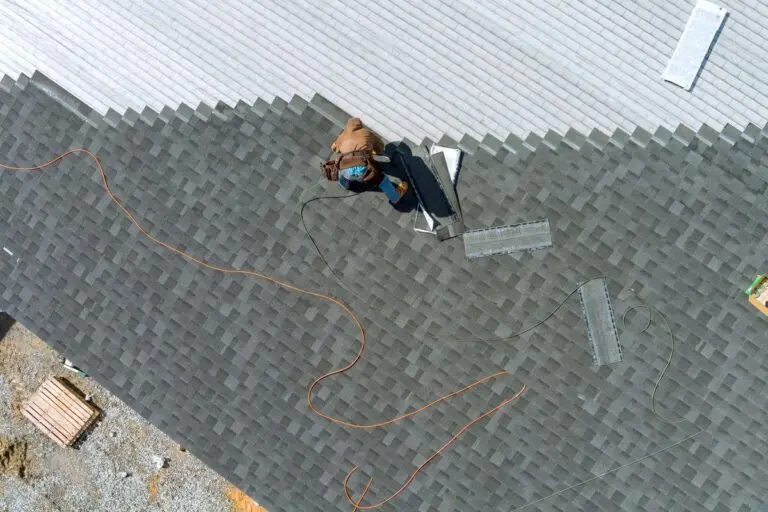 An asphalt shingles installation on the roof roofer is nailing asphalt shingles to roofing construction