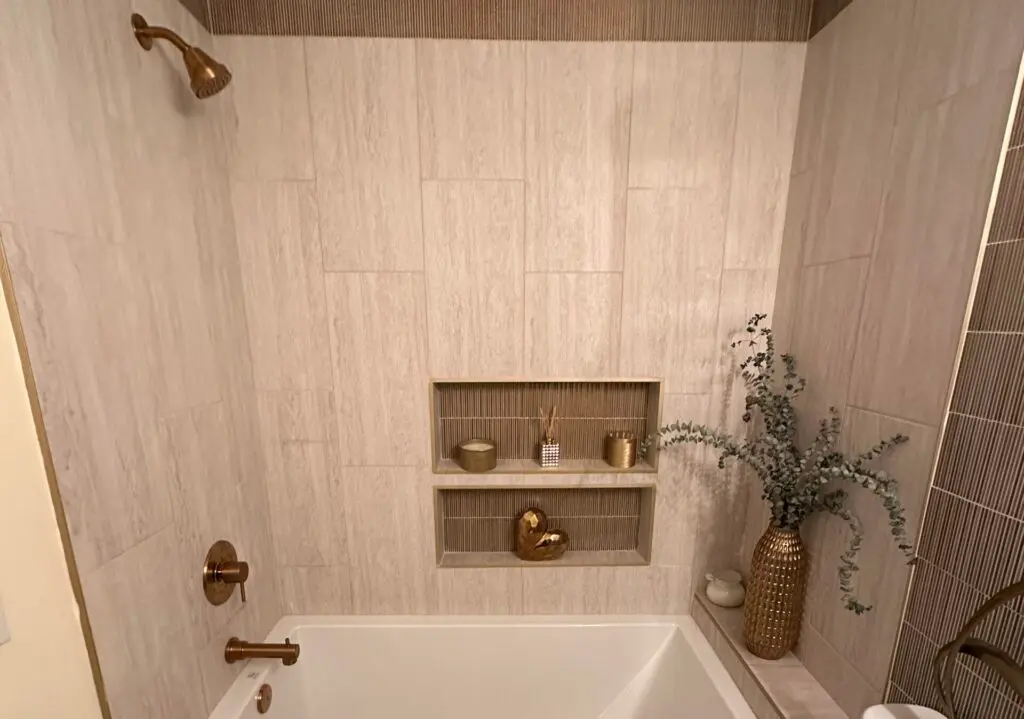 Built in shelves in the shower, above a bath tub. Shower with gold accents and decorations.
