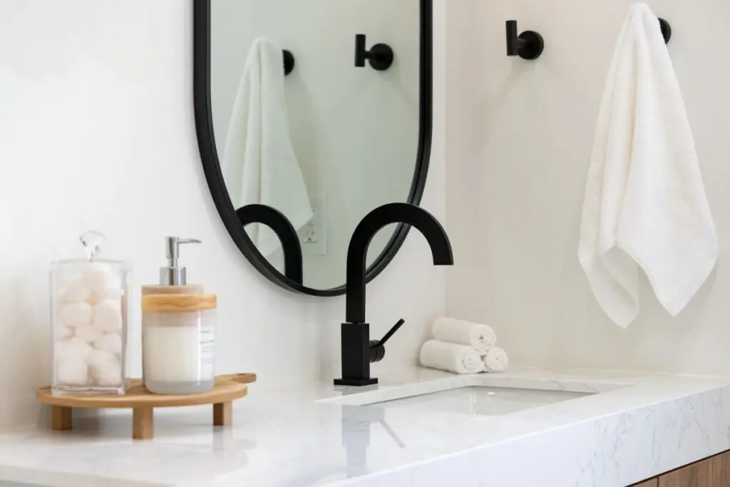 Modern bathroom details of sink with black faucet, black rim mirror