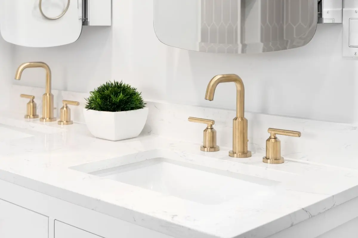 A bathroom detail with gold faucets, white vanity cabinet