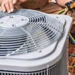 Technician repairing an air conditioning unit with tools and hoses, representing HVAC services by Air Works Heating & Air.