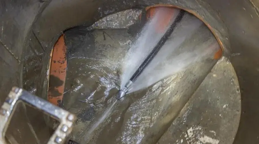 High-pressure water jetting system inside metal pipe, used for HVAC duct cleaning and maintenance by Air Works Heating & Air.