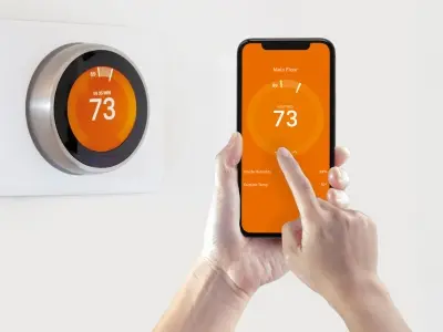 Smart thermostat display showing temperature settings, with a user adjusting settings via smartphone app, illustrating energy efficiency and automated temperature control.