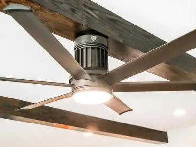 Ceiling fan with light fixture and wooden beams, illustrating energy-efficient climate control tips for homeowners.