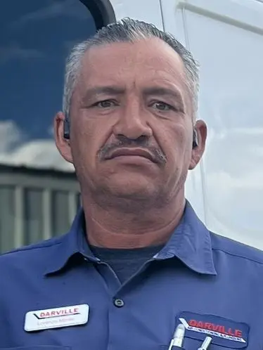 Male Darville Company technician in blue uniform with tools and name tag, showcasing HVAC and plumbing expertise.