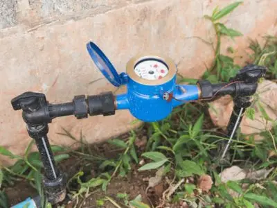 Water meter installed in the ground surrounded by grass, used for monitoring water usage and detecting leaks in plumbing systems.