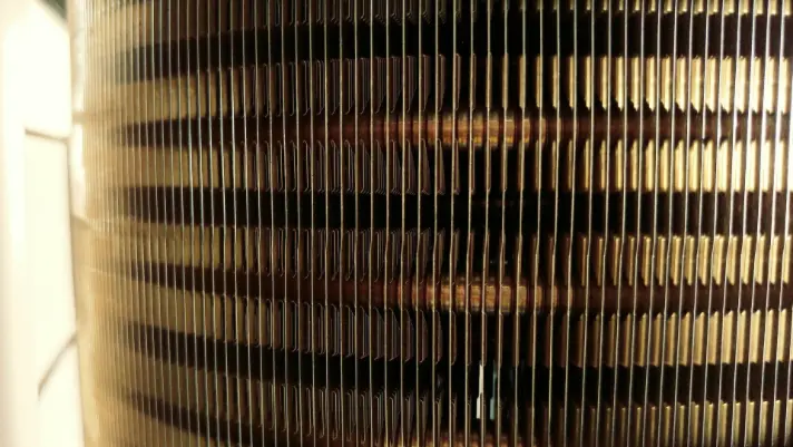 Close-up of HVAC condenser coils showing detailed metal fins, emphasizing air conditioning maintenance and repair services relevant to The Darville Company.