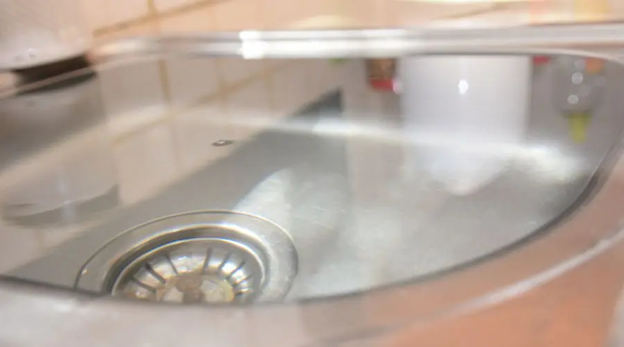 Kitchen sink with standing water, indicating potential sewer line backup issue, relevant to plumbing emergencies and home damage prevention.