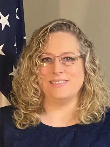Angela Duran, Accounts Receivable team member at The Darville Company, smiling in front of an American flag backdrop.