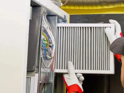Technician replacing air filter in a heating system, emphasizing the importance of regular maintenance for optimal performance and longevity.