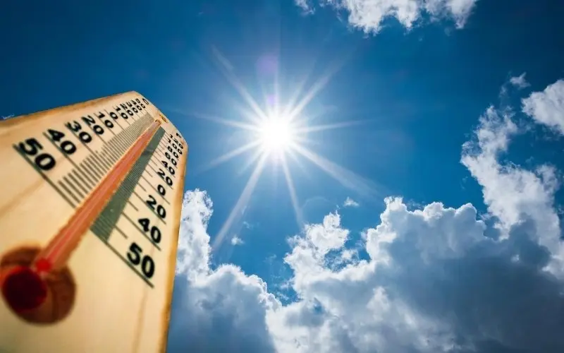 Thermometer showing high temperature under a clear blue sky, highlighting summer heat and A/C maintenance.