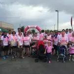 Diverse group of participants in pink attire at charity walk, showcasing community involvement and support for a cause.