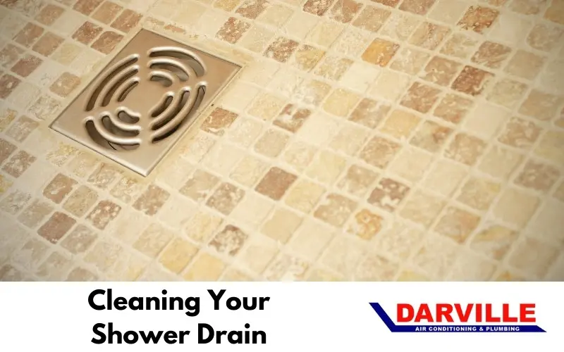 Cleaning shower drain with tiled floor and Darville branding, emphasizing plumbing maintenance tips.