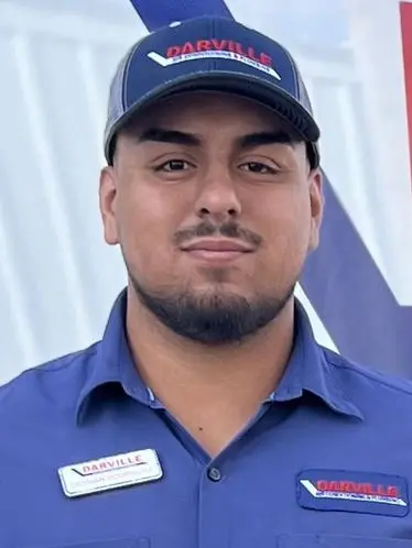Young man in blue work shirt and cap representing The Darville Company, showcasing professionalism and HVAC expertise.
