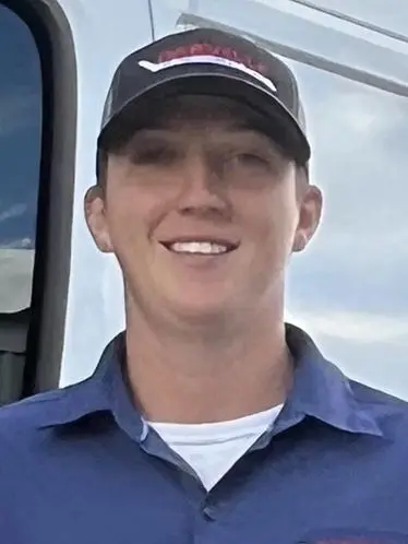Young man in a cap and collared shirt representing The Darville Company team in an outdoor setting.