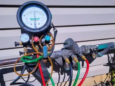 Backflow testing equipment with pressure gauge and hoses, used for ensuring backflow preventer functionality in municipal water systems.