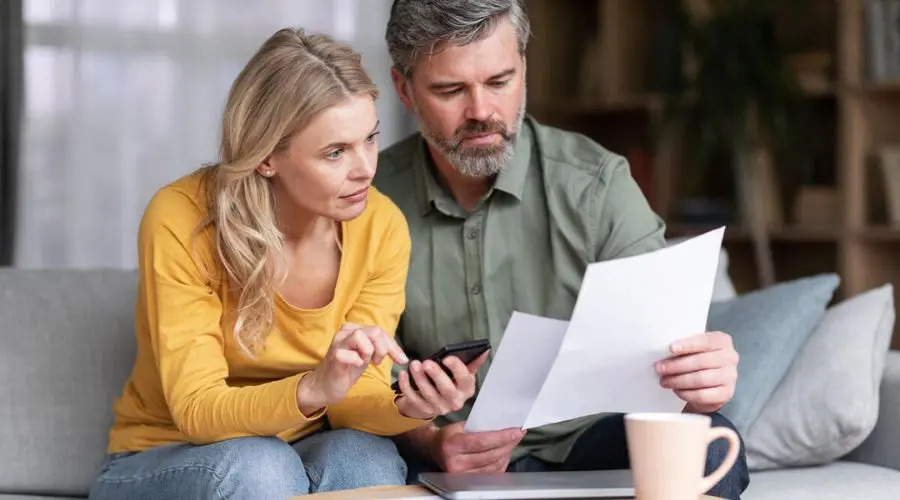 Couple reviewing utility bills together at home, discussing ways to save on costs and maintain comfort during rising utility expenses.