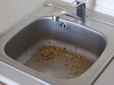 Clogged kitchen sink with food debris, illustrating potential causes of sewer line backups and the importance of proper maintenance.