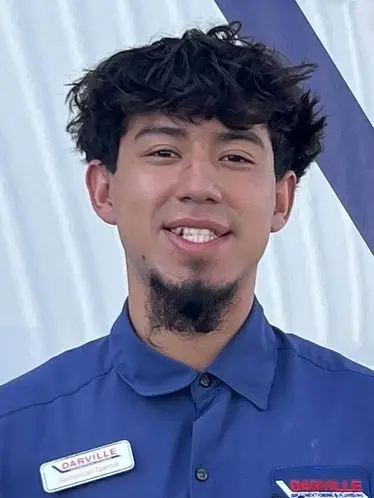 Young man in a blue shirt with a name tag "DARVILLE" representing The Darville Company team. Simple diagonal line background.