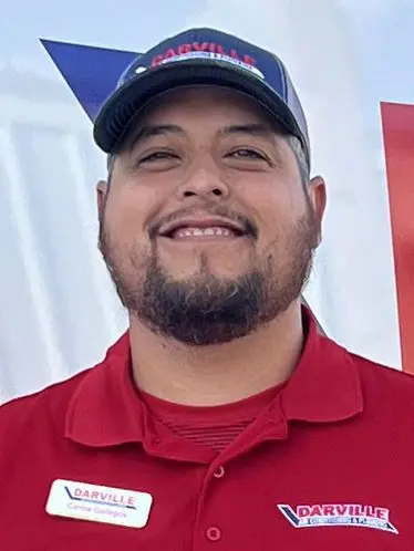 Team member Carrol Gutierrez in a red polo shirt, smiling with a name tag at The Darville Company.