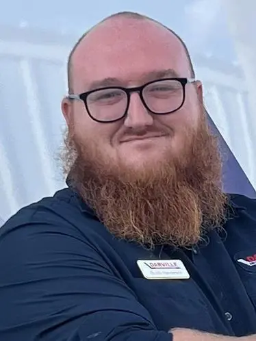 Man with a beard and glasses in a dark shirt with a name tag at The Darville Company, showcasing HVAC and plumbing expertise.