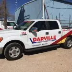 Pickup truck with "Davenport" branding and contact number, parked outside The Darville Company's service facility.