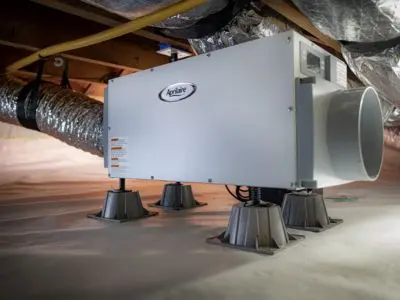 Whole-house dehumidifier installed in a crawl space, featuring cooling coils and ductwork for moisture removal and air circulation.
