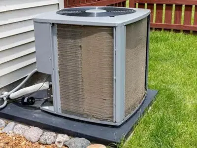 Dirty air conditioning unit with visible debris on coils, indicating potential low refrigerant and airflow issues, relevant to HVAC maintenance and repair.