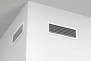 HVAC system vents installed in a corner wall, showcasing the importance of maintaining airflow for efficient heating and cooling.