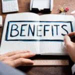 Hand writing in a notebook titled "BENEFITS" with a ruler and calculator on a desk. HVAC planning and organization.