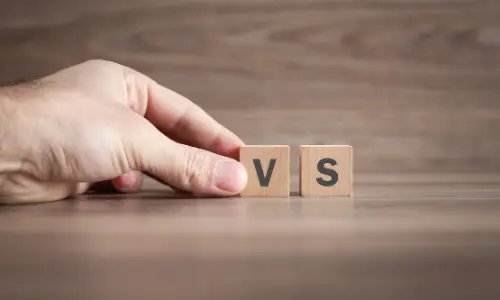 Hand holding wooden blocks with "VS" on a wooden surface, representing a comparison between air purifiers and air sanitizers in the context of improving indoor air quality.