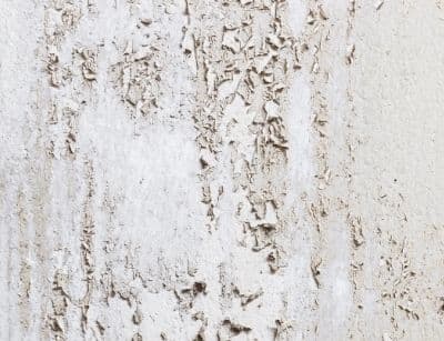 Peeling paint on a wall indicating excess moisture and potential mold growth, relevant to indoor air quality concerns.