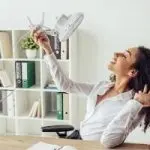 Smiling woman in white shirt at modern office desk with HVAC service documents and fan for Chad's AC Direct.