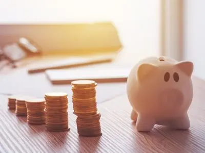 Piggy bank next to stacks of coins, symbolizing savings and lower monthly bills related to new air conditioning costs.