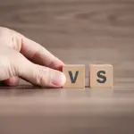 Hand holding wooden blocks with letters "V" and "S" for HVAC service comparison at Chad's AC Direct in Montgomery, Alabama.