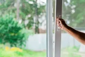 Hand opening a window to improve indoor air quality and ventilation for allergy relief.