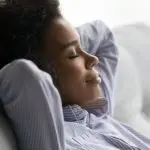 Young child with curly hair relaxing on a couch, representing comfort in a cozy setting related to HVAC services.