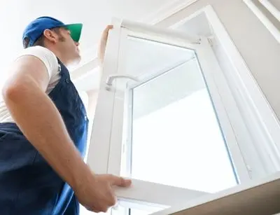 Man installing an Energy Star window, emphasizing home energy efficiency and draft repair.