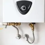 Water heater with control dial and metal pipes, essential for HVAC maintenance at Chad's AC Direct in Montgomery, AL.