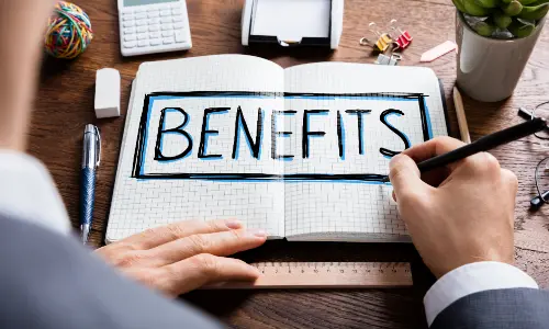 Person writing "BENEFITS" in a notebook, emphasizing the advantages of heat pumps in HVAC systems, with office supplies and a calculator visible in the background.