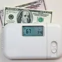 Thermostat showing 67&deg;F with a hundred-dollar bill behind, relating to Chad's AC Direct's HVAC services.