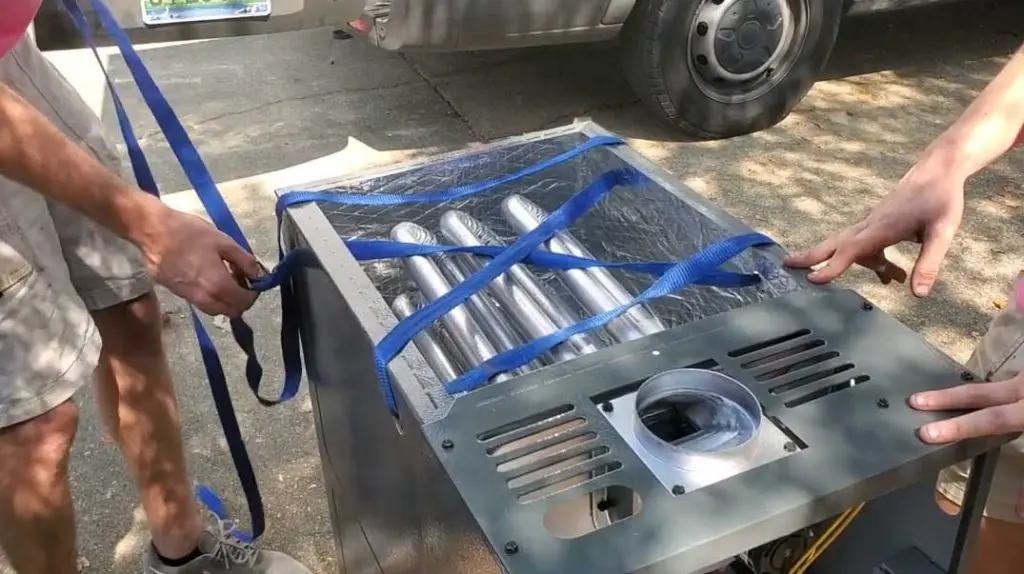Two technicians securing a heating unit with blue straps, preparing for installation, in a residential setting, relevant to Chad's AC Direct heating services.