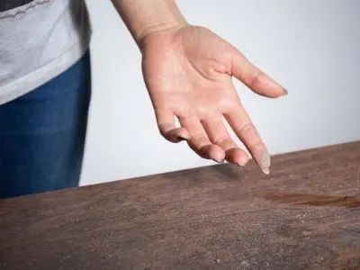 Hand pointing at a dusty surface, illustrating the effects of poor indoor air quality and the need for duct cleaning to reduce allergens and pollutants.