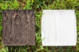 Used and clean air filters side by side on grass, illustrating the importance of regular HVAC maintenance for improved indoor air quality.