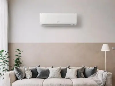 Ductless mini-split air conditioning unit mounted on wall above a modern sofa in a stylish living room, illustrating flexible temperature control for individual rooms.